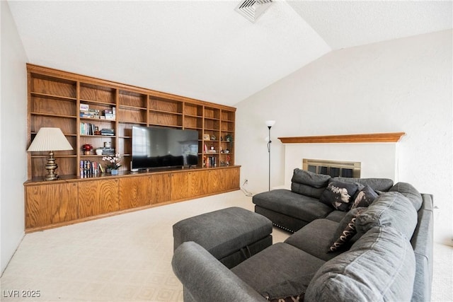 carpeted living room featuring a glass covered fireplace, visible vents, and vaulted ceiling