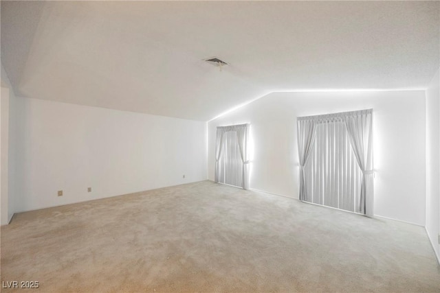 bonus room with light carpet, vaulted ceiling, and visible vents