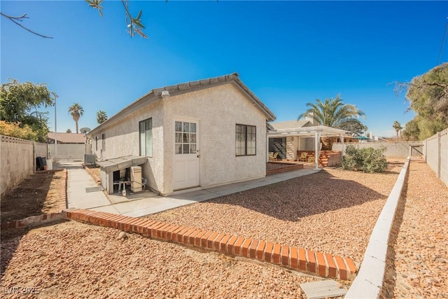 rear view of property featuring a patio, stucco siding, a pergola, cooling unit, and a fenced backyard