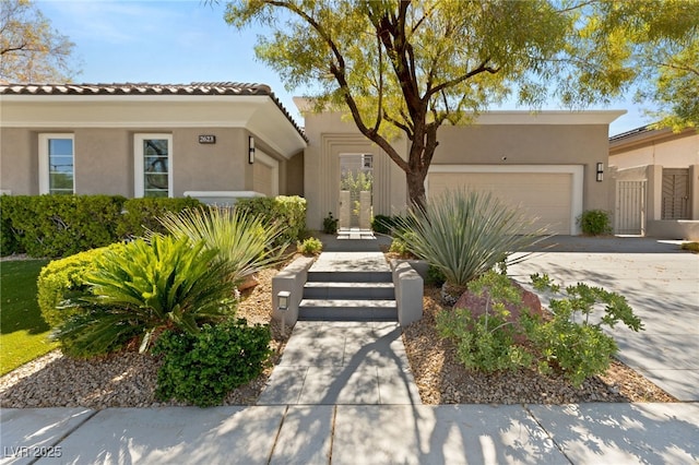 view of front facade with an attached garage, a gate, concrete driveway, and stucco siding