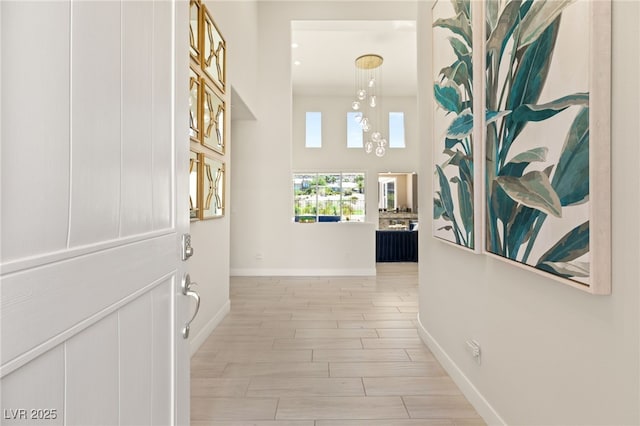 hallway with a chandelier, wood finish floors, and baseboards