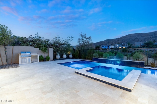 view of pool with a patio area, a fenced backyard, a mountain view, and exterior kitchen