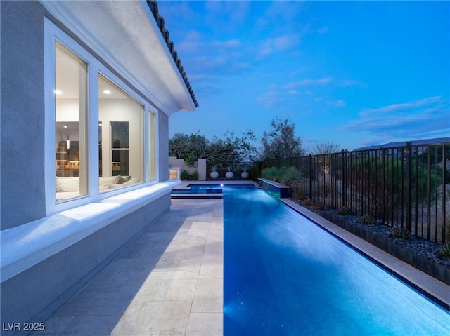 pool at dusk featuring a fenced in pool, a patio area, and a fenced backyard