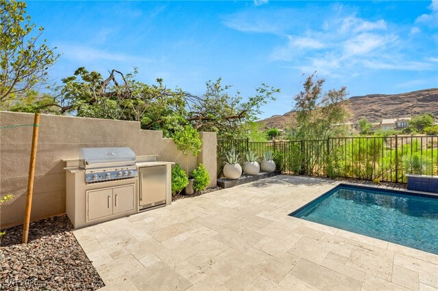 view of swimming pool with a fenced backyard, a mountain view, a patio, and area for grilling