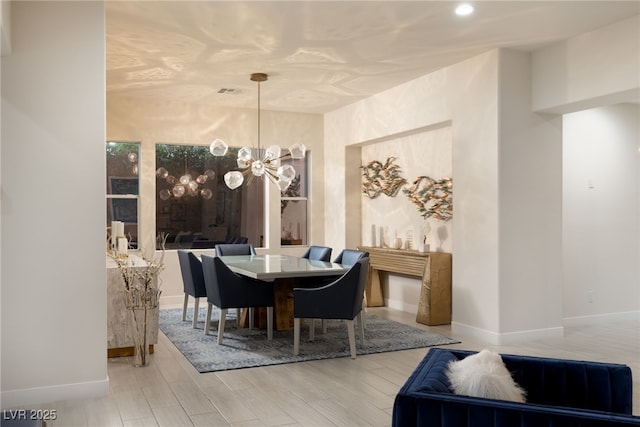 dining space featuring baseboards, wood finished floors, visible vents, and a notable chandelier