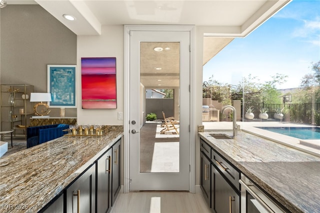 interior space featuring stone counters, a sink, and light wood-style flooring