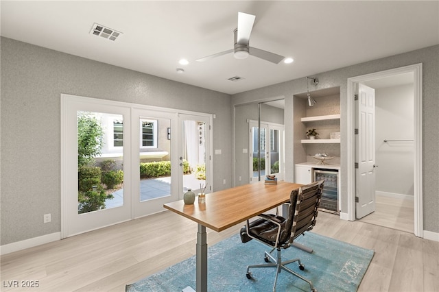 home office featuring baseboards, visible vents, wine cooler, french doors, and light wood-style floors