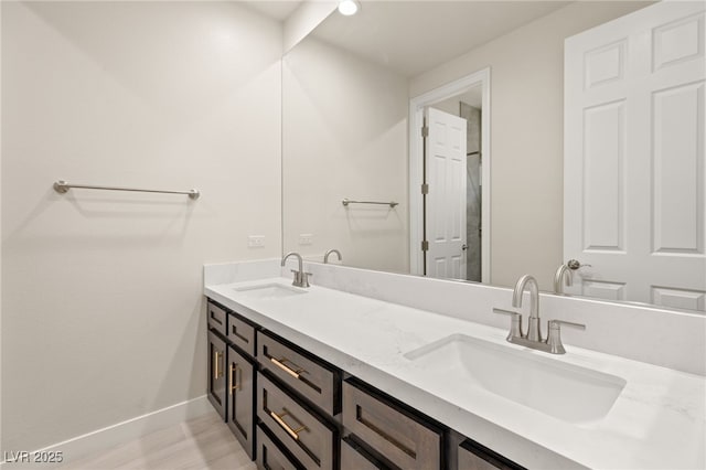 full bathroom featuring a sink, baseboards, and double vanity