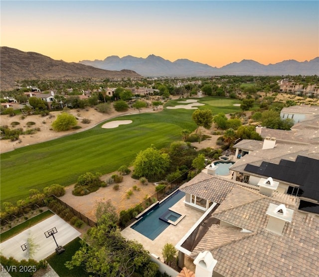 aerial view at dusk with view of golf course and a mountain view