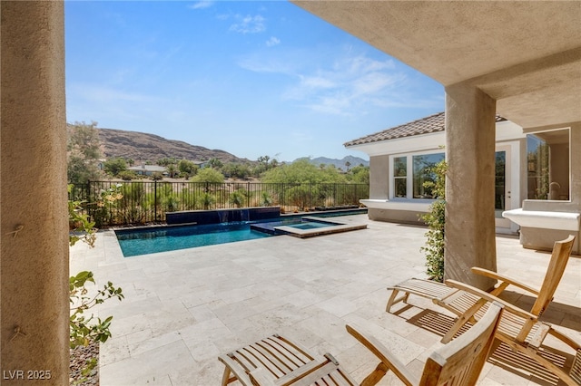 view of pool with a pool with connected hot tub, a patio area, a fenced backyard, and a mountain view