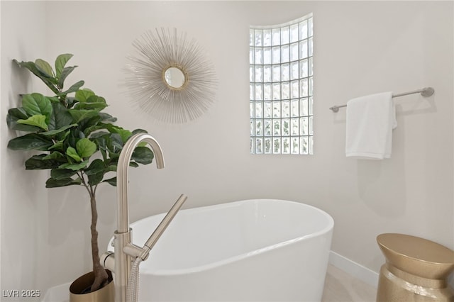 full bathroom with a freestanding bath and baseboards