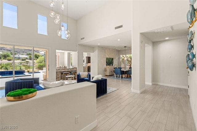 living area featuring baseboards, light wood-style floors, visible vents, and an inviting chandelier