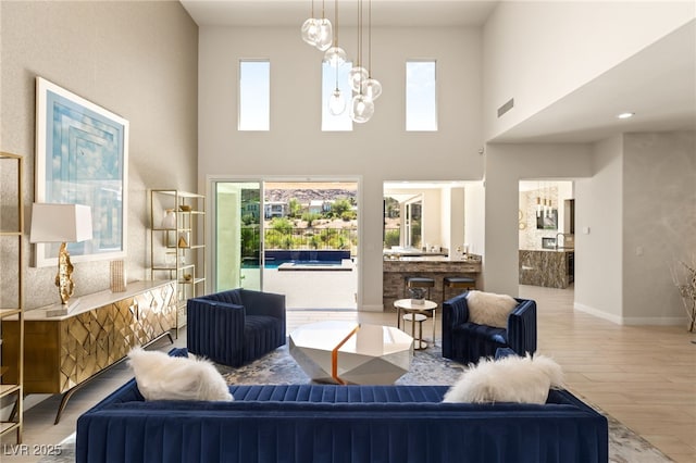 living area featuring visible vents, a notable chandelier, baseboards, and wood finished floors