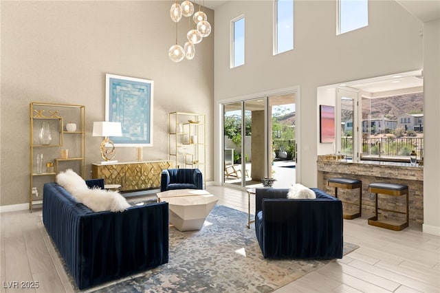 living area with baseboards, a chandelier, and wood finished floors