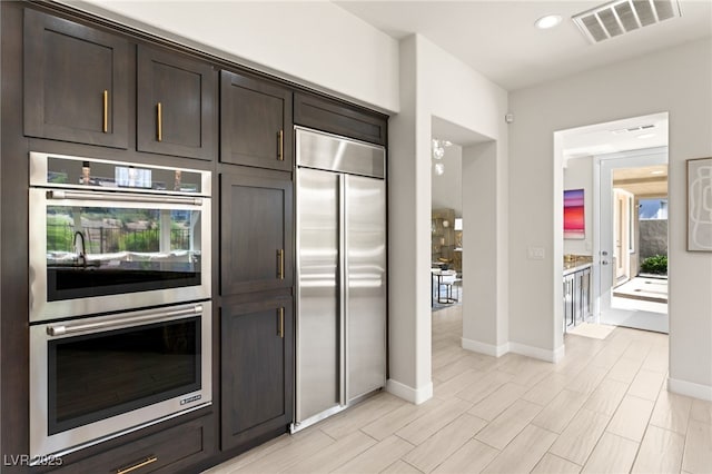 kitchen featuring stainless steel appliances, visible vents, light wood-style floors, dark brown cabinetry, and baseboards