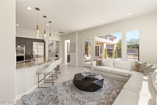 living room with light wood-type flooring, recessed lighting, visible vents, and baseboards