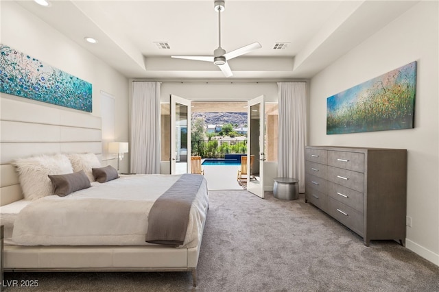 bedroom featuring ceiling fan, visible vents, access to exterior, a tray ceiling, and carpet