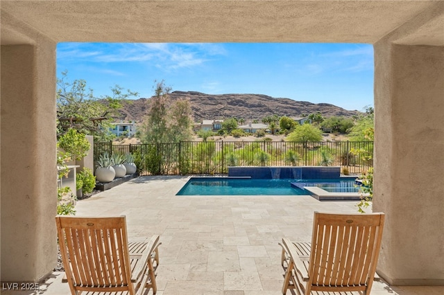 view of pool featuring a pool with connected hot tub, a fenced backyard, a mountain view, and a patio