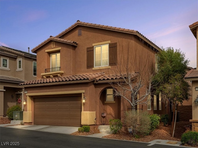 mediterranean / spanish house with driveway, an attached garage, and stucco siding