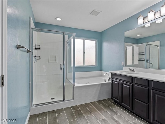 full bath featuring a stall shower, a sink, a bath, and wood tiled floor