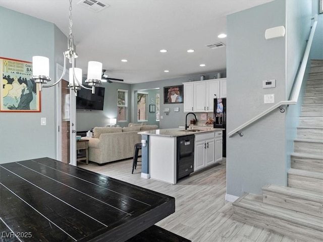 kitchen with white cabinets, visible vents, a sink, and open floor plan