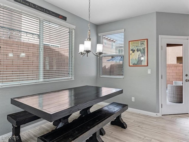 dining room with baseboards, light wood finished floors, and an inviting chandelier