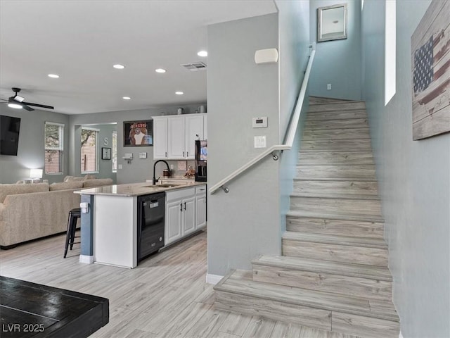 kitchen with black dishwasher, visible vents, open floor plan, white cabinetry, and a sink