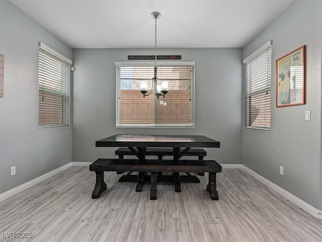 dining area featuring a notable chandelier, light wood-style flooring, and baseboards