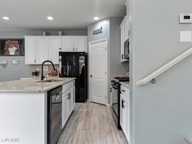 kitchen with black appliances, a sink, white cabinetry, and light wood-style floors