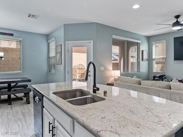 kitchen featuring a sink, visible vents, white cabinets, open floor plan, and black dishwasher