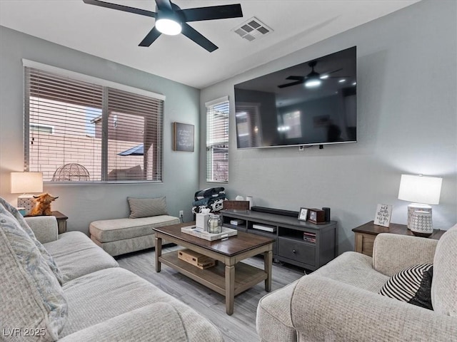 living area featuring a ceiling fan, visible vents, and wood finished floors