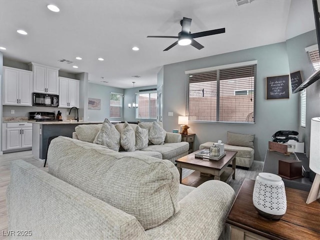 living room featuring light wood-type flooring, visible vents, and recessed lighting