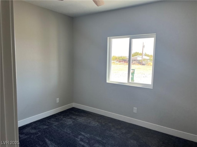empty room with baseboards, dark carpet, and a ceiling fan