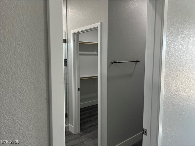 bathroom featuring baseboards, wood finished floors, and a textured wall