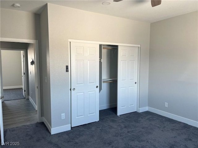 unfurnished bedroom with a ceiling fan, baseboards, dark carpet, and a closet