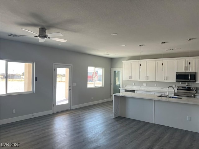 kitchen featuring appliances with stainless steel finishes, a sink, white cabinetry, and a healthy amount of sunlight