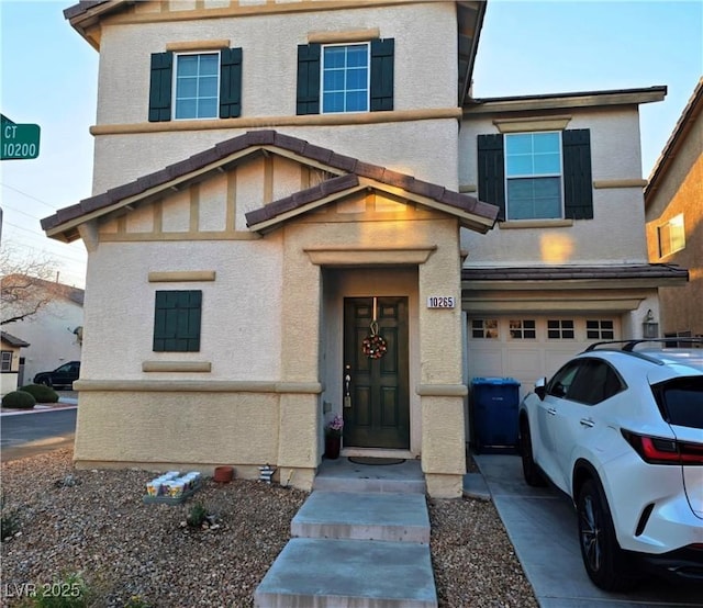 view of front of house with a garage, concrete driveway, and stucco siding