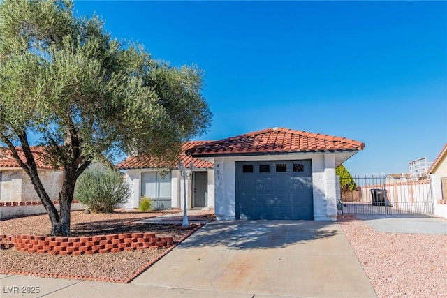 mediterranean / spanish home with a tile roof, stucco siding, concrete driveway, an attached garage, and fence