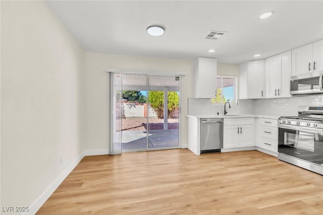 kitchen featuring visible vents, decorative backsplash, appliances with stainless steel finishes, light countertops, and light wood-type flooring