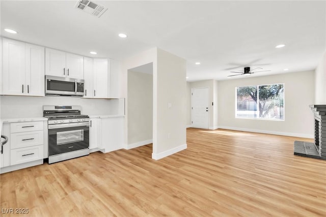 kitchen with stainless steel appliances, light countertops, white cabinets, and visible vents