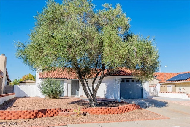 view of front of property featuring a tile roof, stucco siding, fence, a garage, and driveway