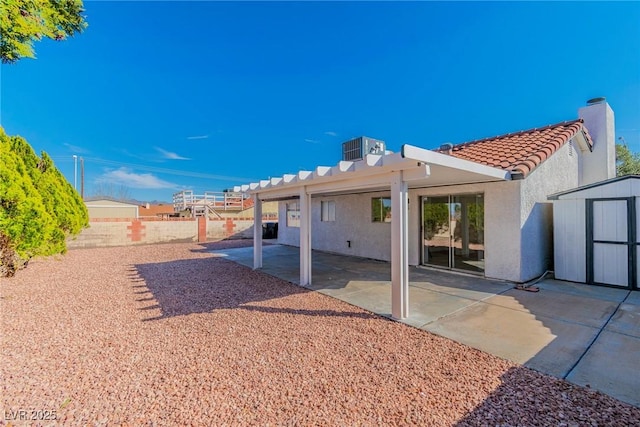 rear view of property featuring central air condition unit, a storage shed, a patio area, an outdoor structure, and a tiled roof