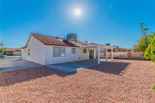 rear view of property with stucco siding, a patio, fence, and central air condition unit