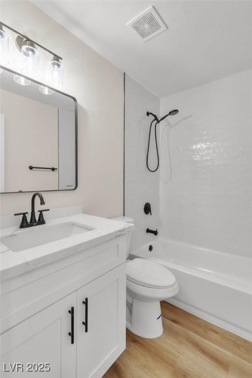 full bath with shower / tub combination, toilet, wood finished floors, vanity, and visible vents