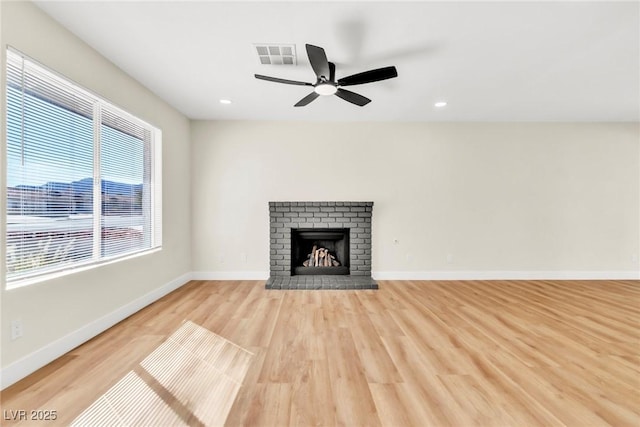 unfurnished living room with a fireplace, wood finished floors, visible vents, and baseboards