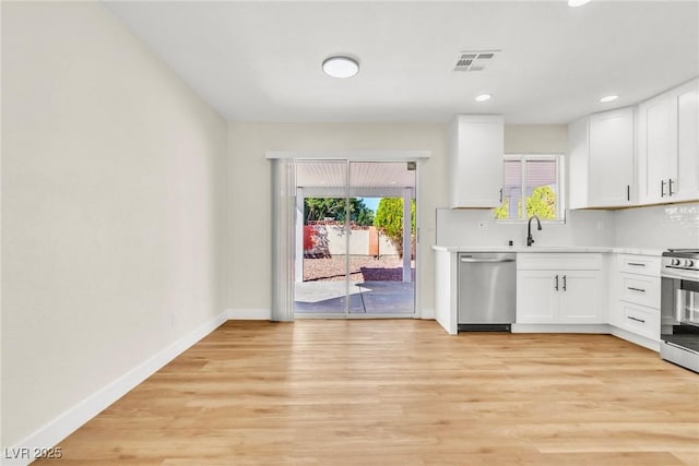 kitchen with light wood-style flooring, appliances with stainless steel finishes, light countertops, and baseboards