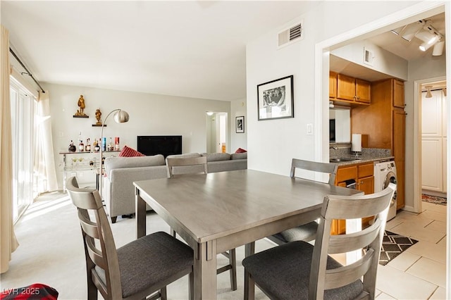 dining area with washer / clothes dryer, visible vents, and light tile patterned flooring