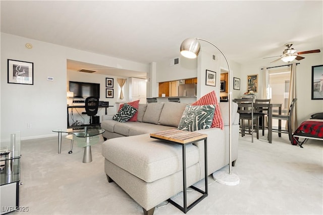 living room with a ceiling fan, visible vents, and light colored carpet