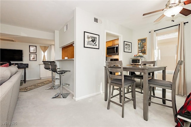 dining space with visible vents, ceiling fan, light carpet, and baseboards