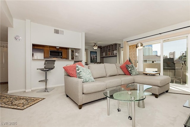 living room with light carpet, baseboards, visible vents, and a ceiling fan